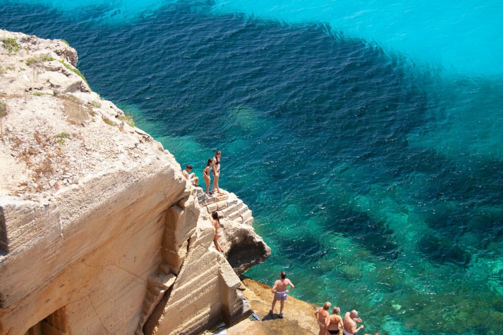 people on brown rock formation near body of water during daytime